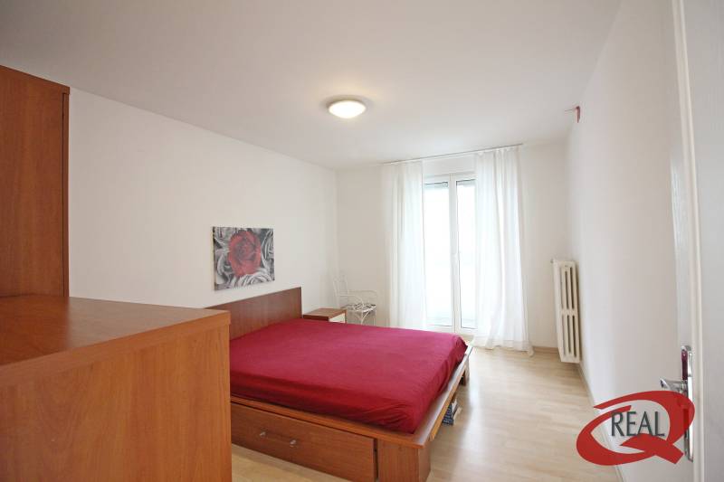 Hálószoba egy háromszobás lakásban, ággyal és fa dekoros padlóval.