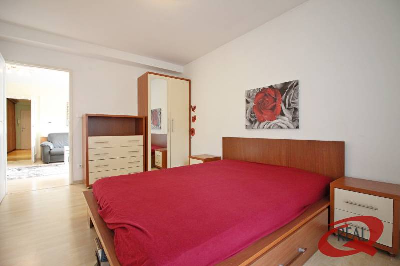 Hálószoba fa mintás padlóval, ággyal, szekrénnyel és képpel egy háromszobás lakásban.