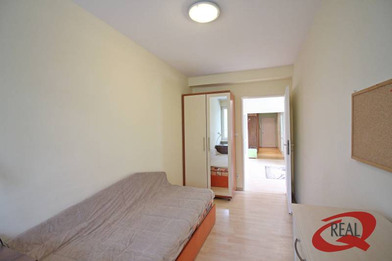 Szoba egy háromszobás lakásban kanapéval, beépített szekrénnyel és fa dekor padlóval.