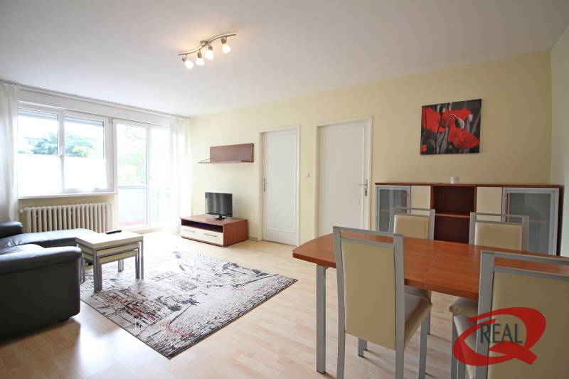 Nappali egy háromszobás lakásban, fa dekoros padlóval, kanapéval és étkezőasztallal.