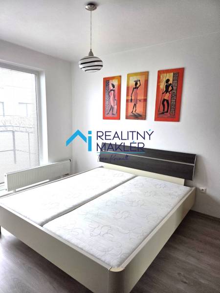 Hálószoba franciaággyal, lámpával és képekkel egy egyszobás lakásban.