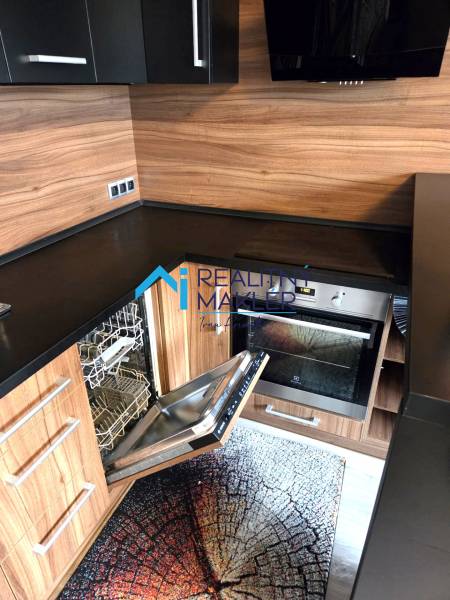 Konyha egy egyszobás lakásban beépített mosogatógéppel és fa dekorációval.