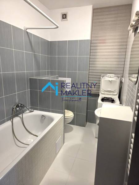 Fürdőszoba káddal, mosdóval és mosógéppel egy egyszobás lakásban.