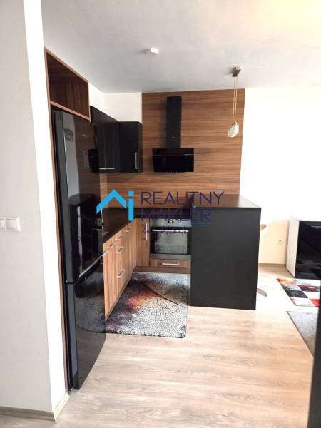 Konyha egy egyszobás lakásban sötét bútorokkal és fa dekorációjú padlóval.