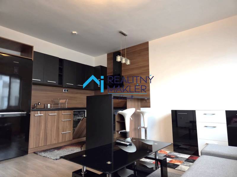 Konyha egy egyszobás lakásban fekete szekrényekkel, fa dekor padlóval.