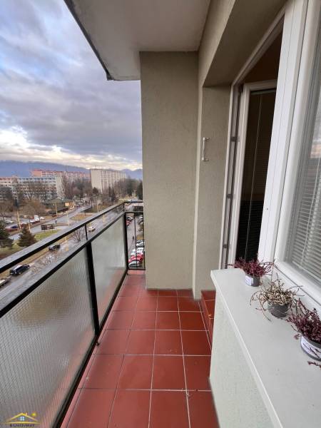 A zsolnai kétszobás lakás erkélye kerámia padlóval és kilátással a környező épületekre.