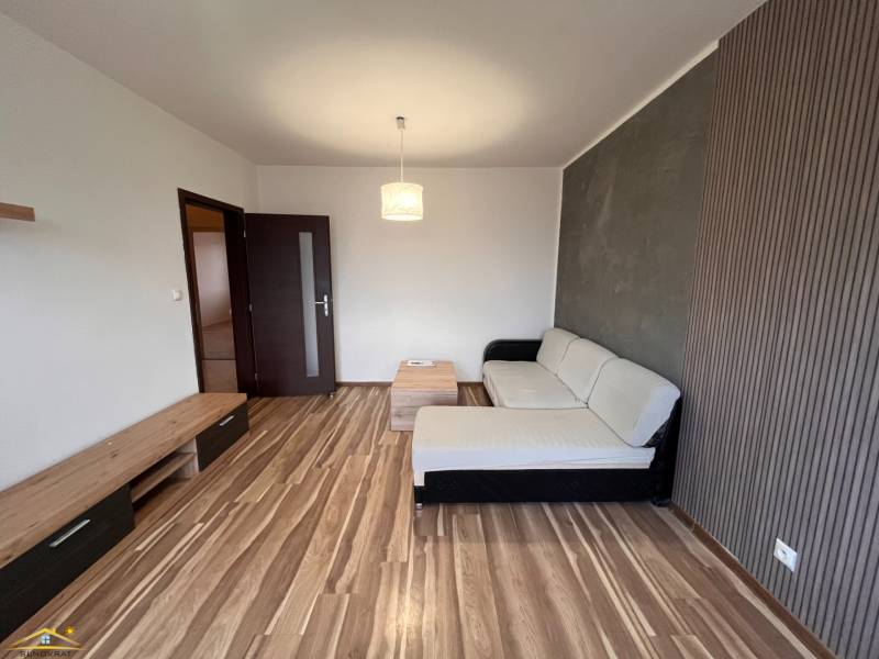 Nappali kanapéval és fa mintázatú padlóval egy kétszobás lakásban.