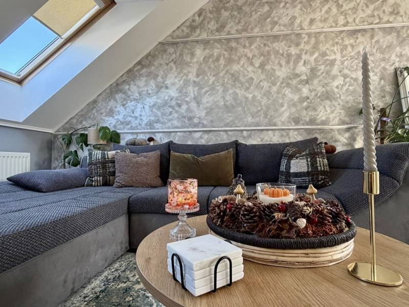 Nappali egy kétszobás lakásban, díszpárnákkal a kanapén és gyertyákkal az asztalon.