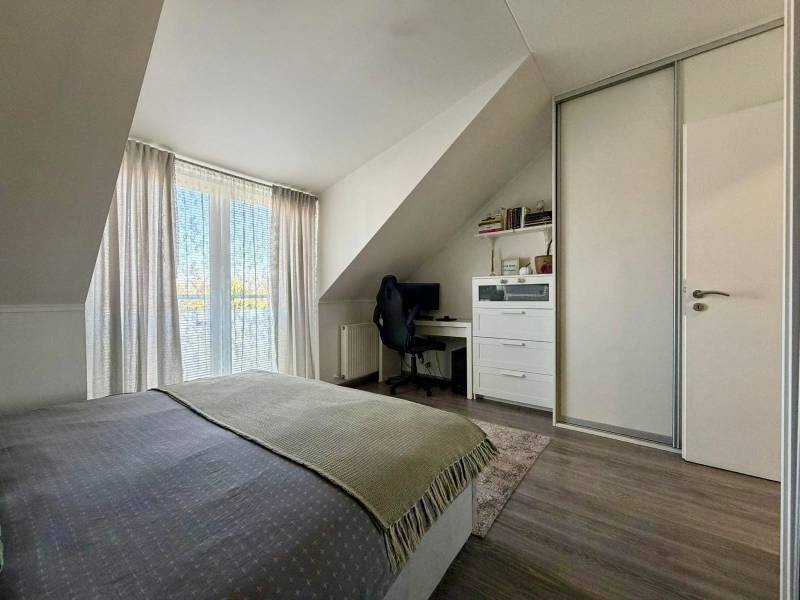 Hálószoba egy kétszobás lakásban íróasztallal és fa mintázatú padlóval.