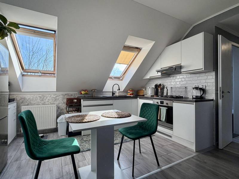 Konyha egy kétszobás lakásban fa dekorációjú padlóval és asztallal székekkel.