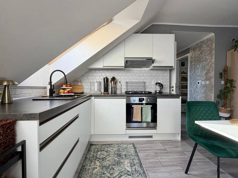 Konyha egy két szobás lakásban ferde mennyezettel és fa dekoros padlóval.