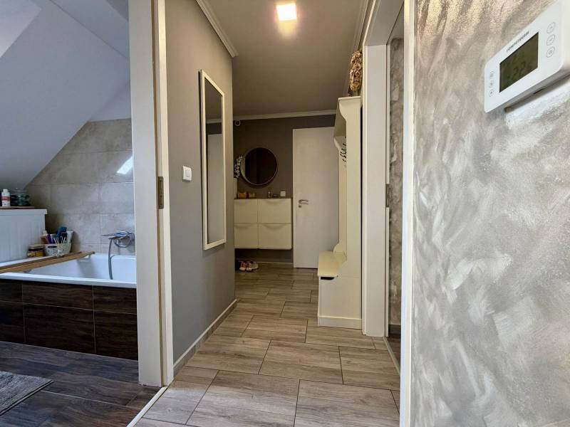 Fürdőszoba egy kétszobás lakásban, fa dekoros padlóval és világos falakkal.