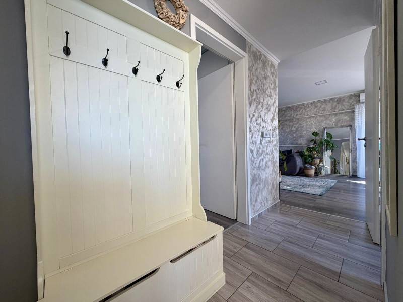 Előszoba egy kétszobás lakásban fogasokkal, amely a nappaliba vezet növényekkel.