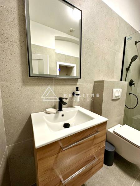 Fürdőszoba egy kétszobás lakásban mosdóval, tükörrel és zuhanyzóval.