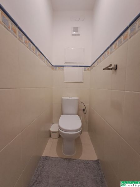 WC csempével és kék-sárga burkolattal egy háromszobás lakásban.