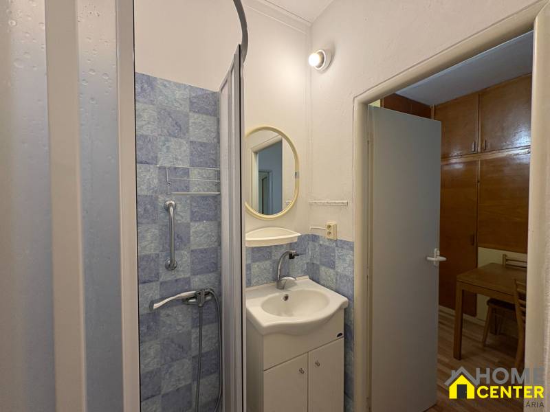 Fürdőszoba egy háromszobás lakásban kék csempékkel és zuhanyzóval.