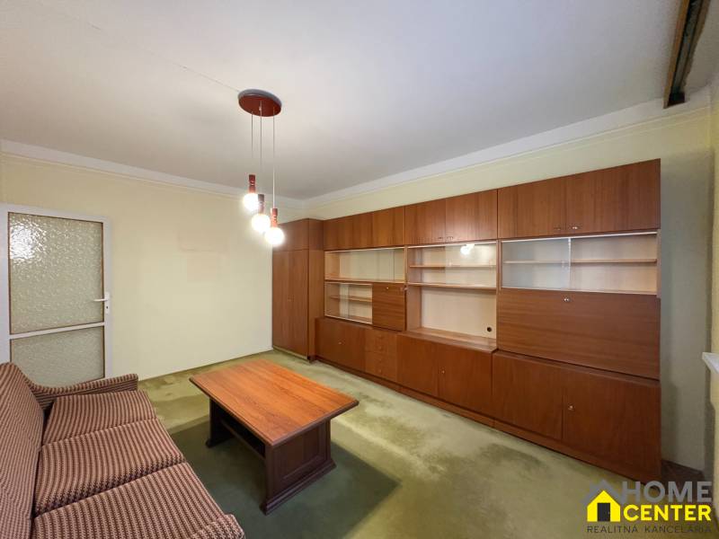 Nappali egy háromszobás lakásban fa faliszekrénnyel és kanapéval.