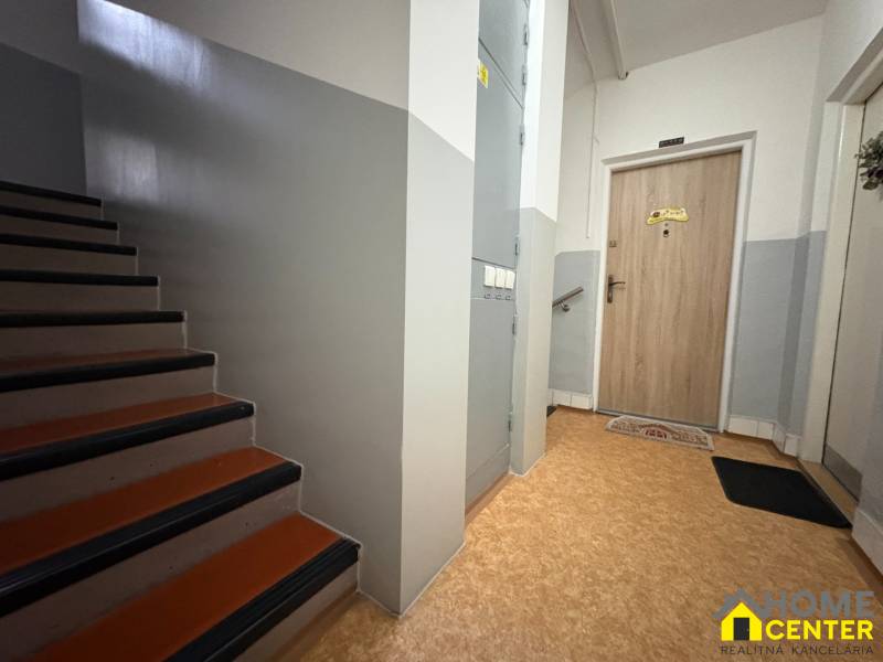 Lépcső és bejárati ajtó egy 3 szobás lakásban, fa dekor padlóval.