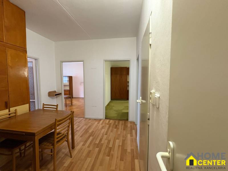 3 szobás lakás belső tere fa dekorációjú padlóval, asztallal és székekkel.