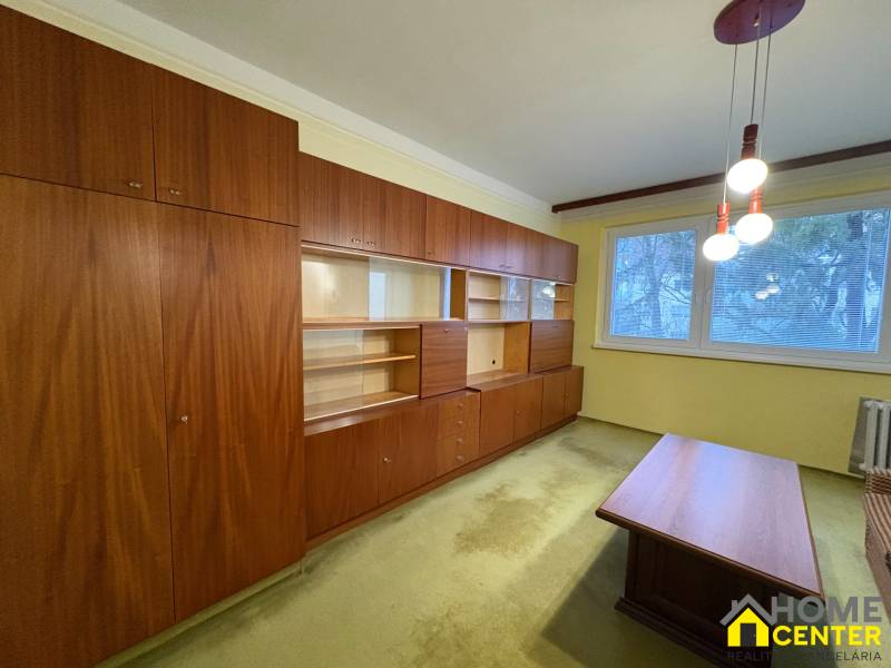 Nappali szoba fa bútorokkal és szőnyeggel egy háromszobás lakásban.