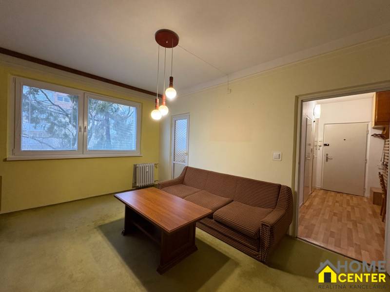 Nappali egy háromszobás lakásban kanapéval és asztallal.