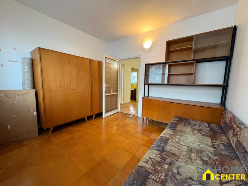 Egy háromszobás lakás szobája fa bútorokkal és fa dekorációjú padlóval.