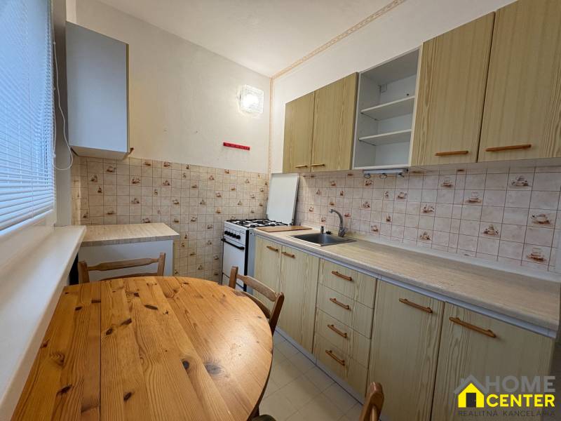 Konyha egy háromszobás lakásban, asztallal, csempével és hangulatos főzőtérrel.