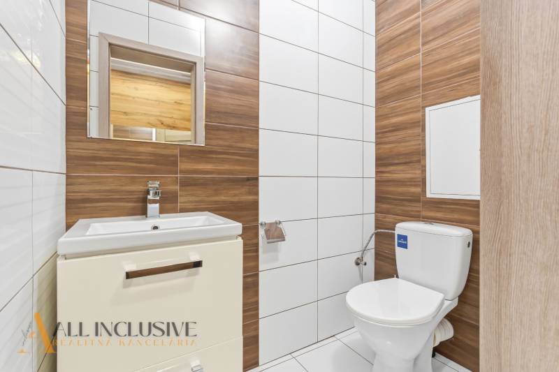 Fürdőszoba kétszobás lakásban WC-vel, mosdóval és fa dekoros csempékkel.