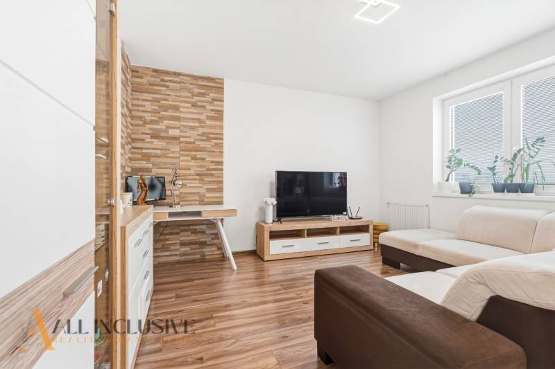 Nappali fa hatású padlóval, TV-vel és krémszínű kanapéval egy kétszobás lakásban.