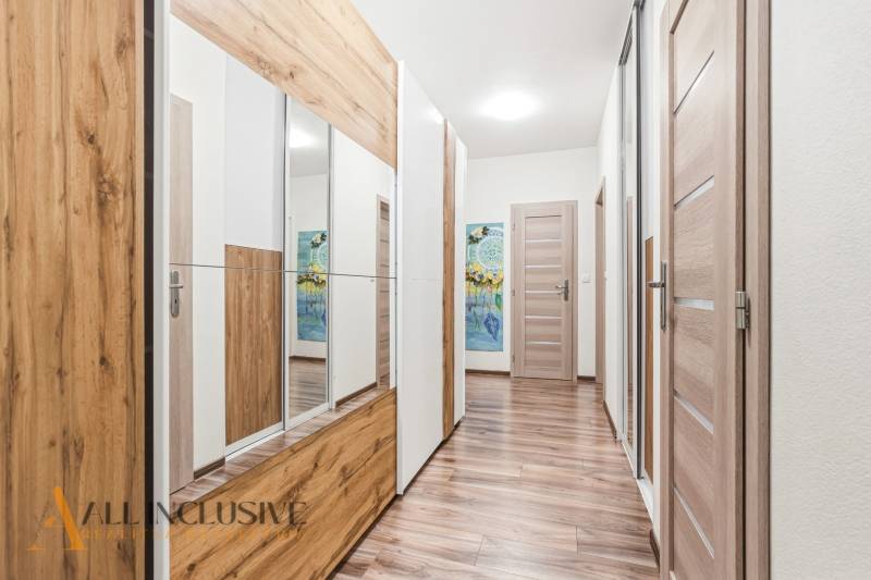 Előszoba egy kétszobás lakásban, fa dekor padlóval és tükrös szekrénnyel.