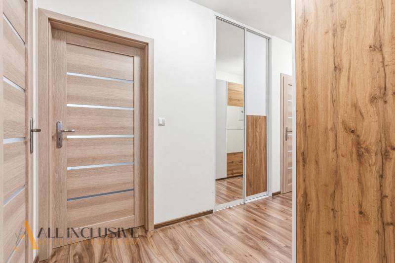 Folyosó egy kétszobás lakásban fa dekoros padlóval és tükrös szekrénnyel.