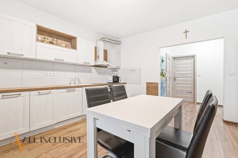 Konyha egy kétszobás lakásban világos szekrényekkel és fa dekorációjú padlóval.