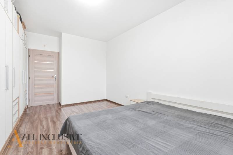 Hálószoba egy kétszobás lakásban fa mintázatú padlóval és tágas szekrénnyel.