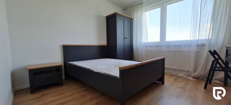 Hálószoba ággyal, szekrénnyel és fa dekoros padlóval egy kétszobás lakásban.