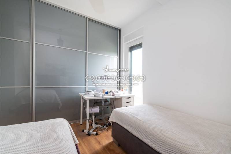 Hálószoba a nyaraló apartmanban tolóajtós szekrénnyel és ággyal, fa dekorációs padlóval.