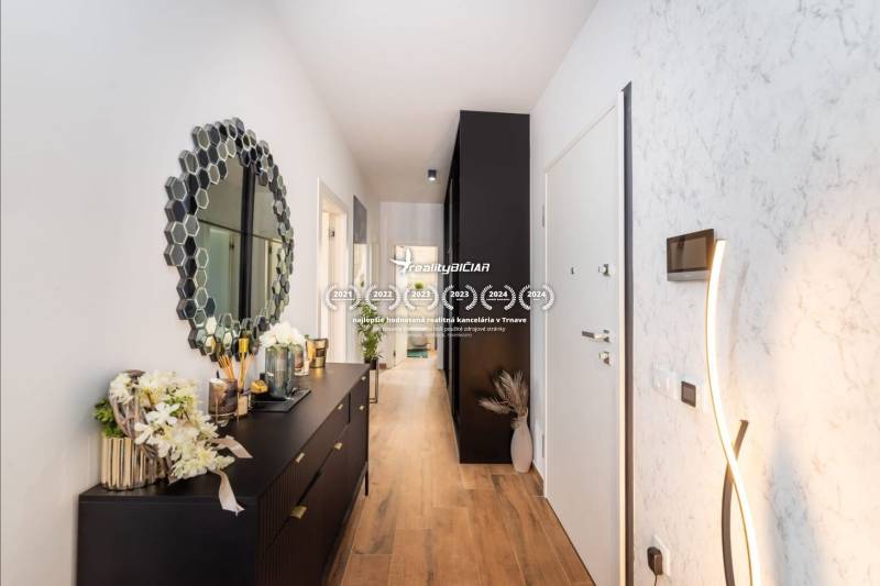 Folyosó fa dekorációjú padlóval és stílusos tükörrel egy üdülő apartmanban.