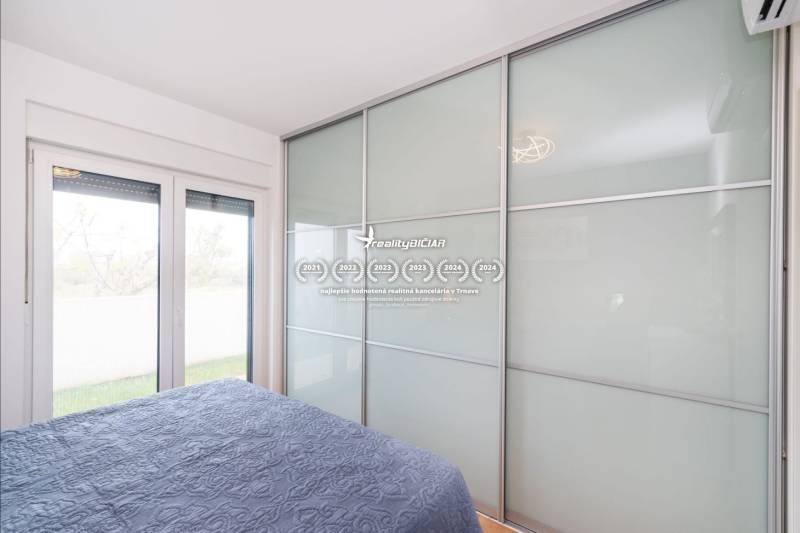 Hálószoba egy üdülőapartmanban nagy beépített szekrénnyel és ággyal kék takaróval.