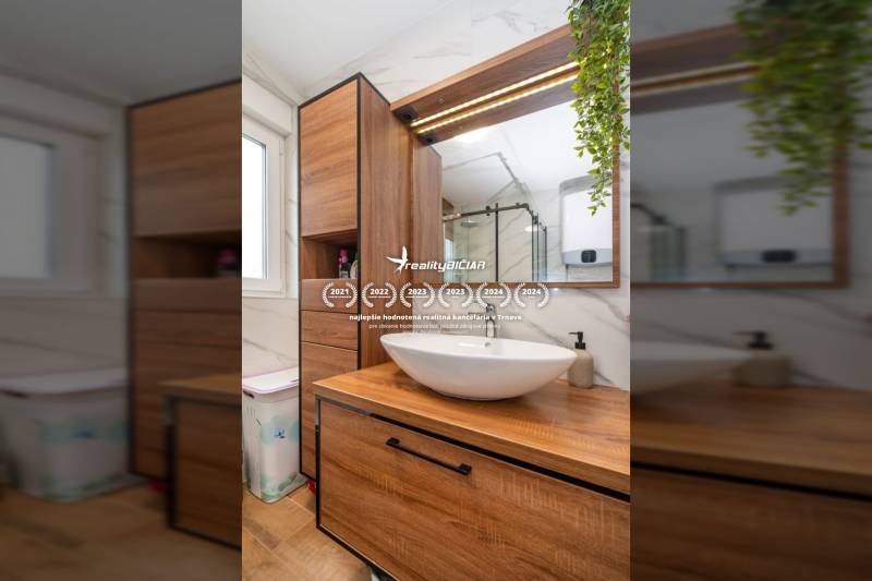 Fürdőszoba egy nyaraló apartmanban mosdóval, fa bútorokkal és fa dekorációjú padlóval.