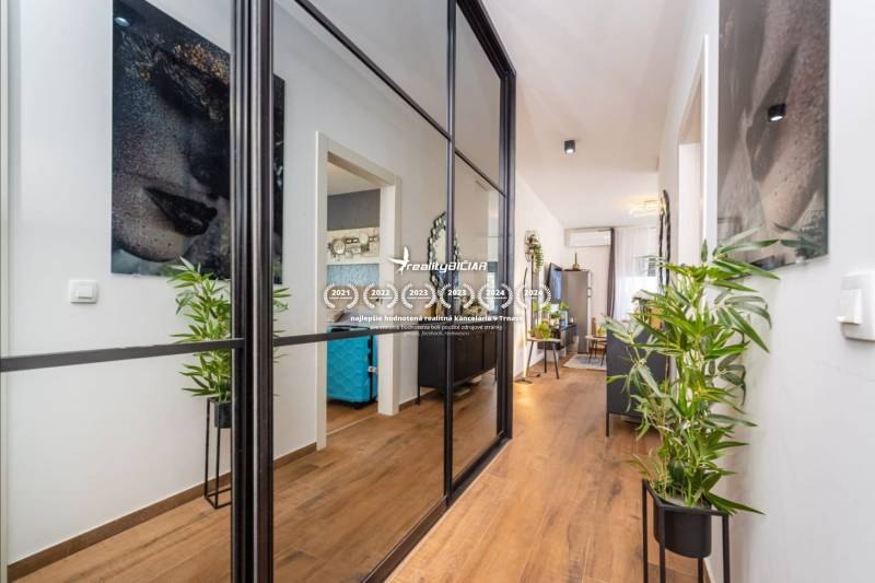 Nyaraló apartman belső tere fa dekor padlóval, tükrös fallal és növényekkel.