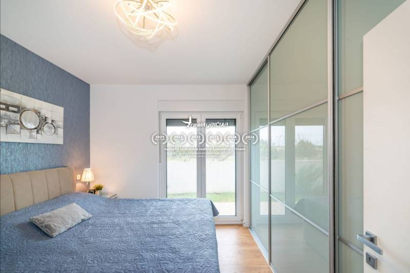 Hálószoba a nyaraló apartmanban fa dekoros padlóval és nagy gardróbbal.