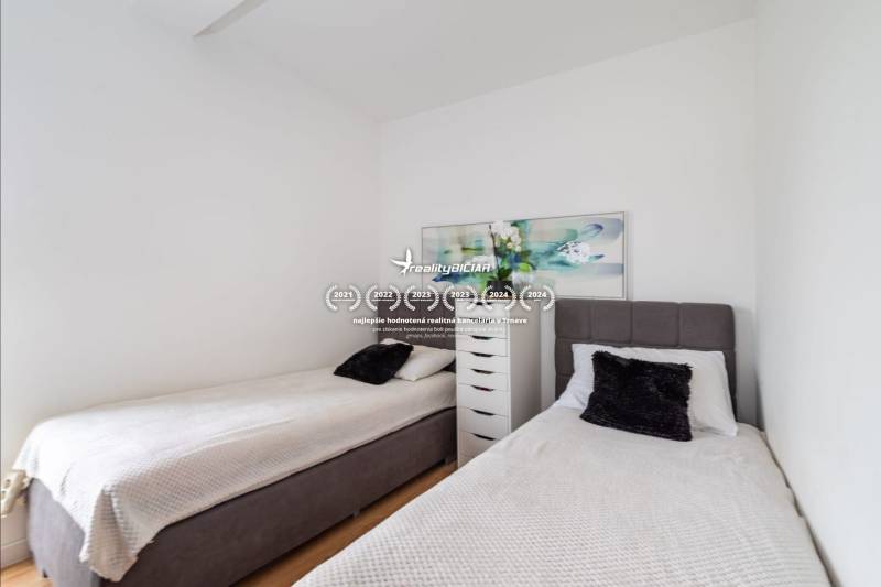 Két egyszemélyes ágy és egy komód a nyaraló apartmanban, fa dekor padlóval.