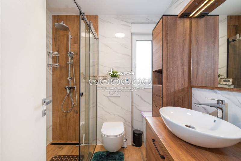 Fürdőszoba egy üdülő apartmanban, fa dekorációjú padlóval és modern felszereléssel.