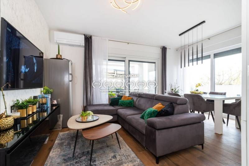 Nappali a nyaraló apartmanban kényelmes kanapéval és fa dekorációjú padlóval.