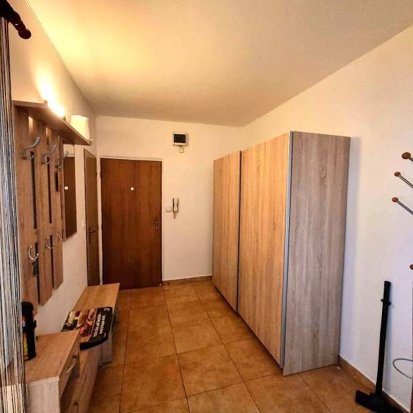 Előszoba egy 2 szobás lakásban fogasokkal, szekrénnyel és fa mintázatú padlóval.