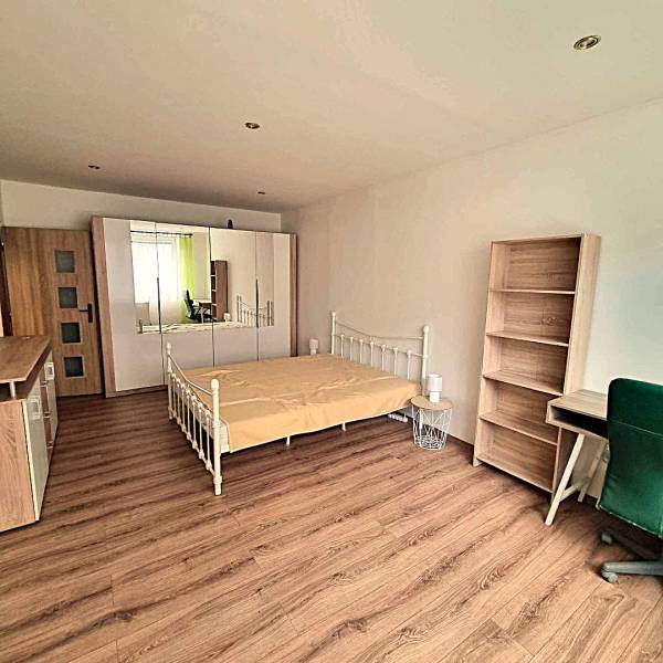 Hálószoba egy kétszobás lakásban ággyal, szekrénnyel és fa dekorációjú padlóval.