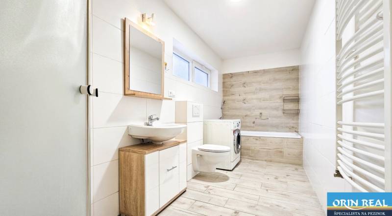 Fürdőszoba egy családi házban fa mintázatú padlóval és mosógéppel.