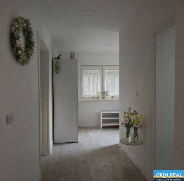 Egy családi ház világos folyosója fa dekoros padlóval, virágokkal és dekorációkkal.