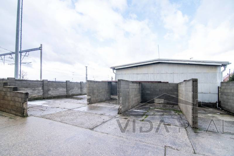 A fényképen a Šenkvice-i Nádražná utcában található raktárak és csarnokok láthatók, szilárd betonfalakkal.