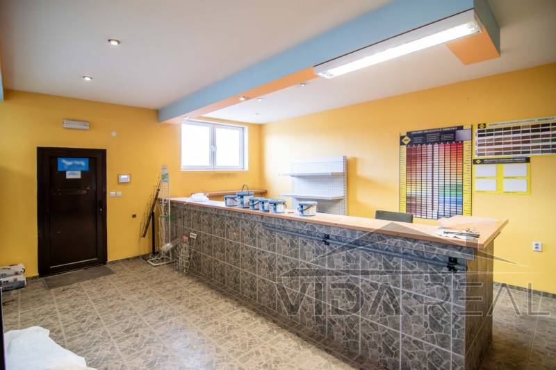 A raktárak és csarnokok belső tere pulttal, polcokkal és színes mintákkal a falon.