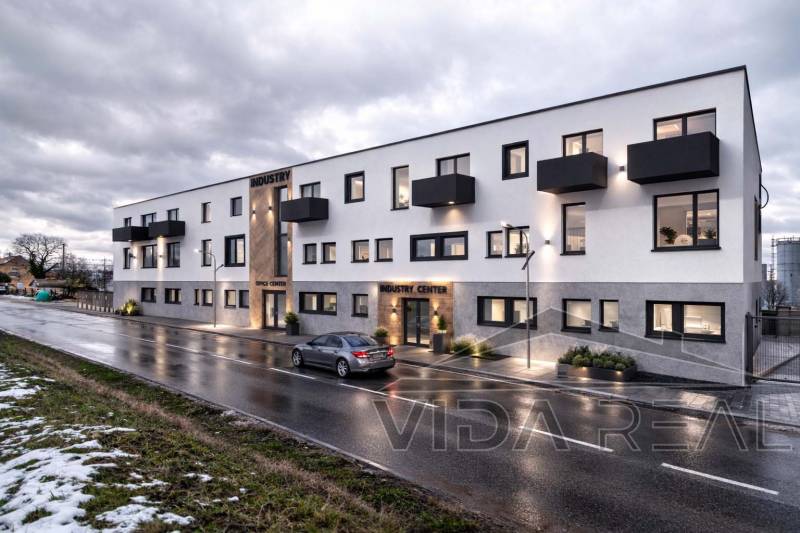 Épület a Šenkvicei Nádražná utcában, raktárak és csarnokok, esti világítással.